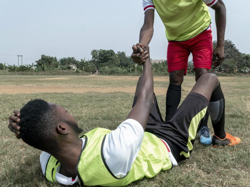 Un joueur de football aidant un coéquipier à se relever sur le terrain