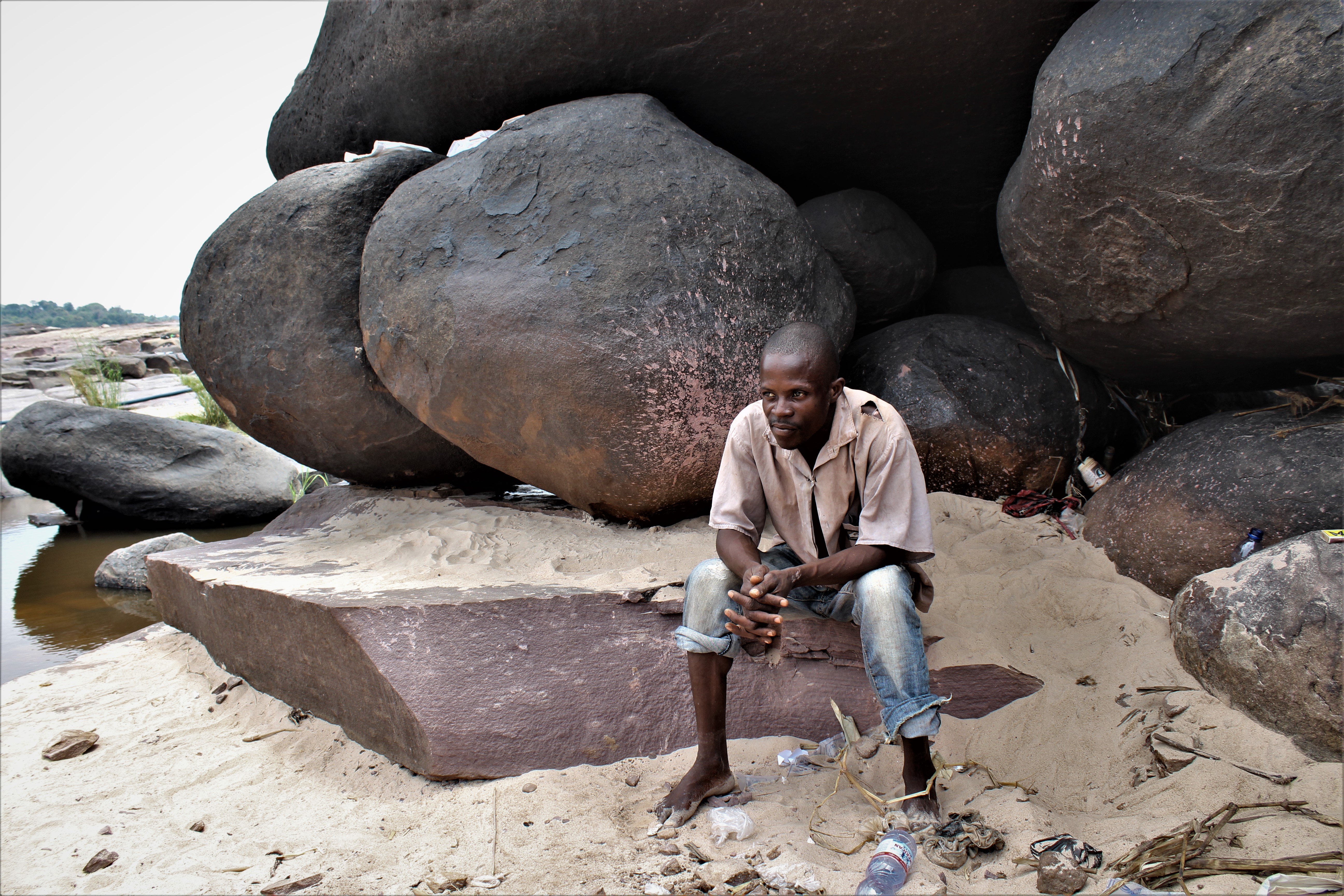 Un artisan se repose sous un bloc de roches, pendant sa pause