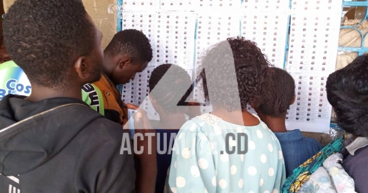 Les électeurs cherchent leurs noms sur les listes affichées au bureau de vote à Kolwezi.