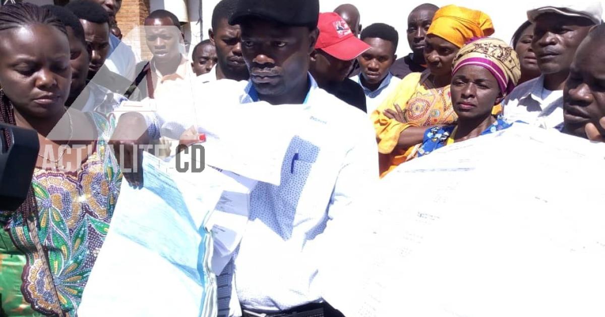 Le CACH Bukavui brandit les bulletins de vote qu'elle affirme avoir ramassé dans une rivère au village Cidodobo.