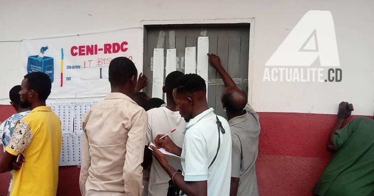 Les électeurs consultent les résultats devant un bureau de vote à Bandundu