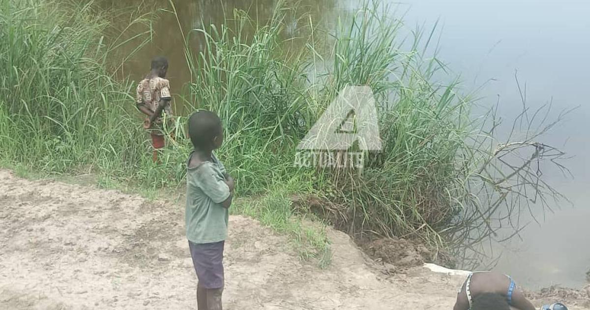 Trois enfants au bord de la rivière N'djili se livrant à la pêche 