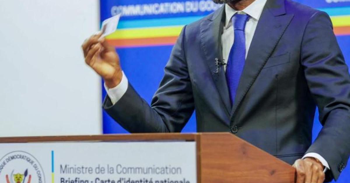 Patrick Muyaya brandissant sa carte d'identité 