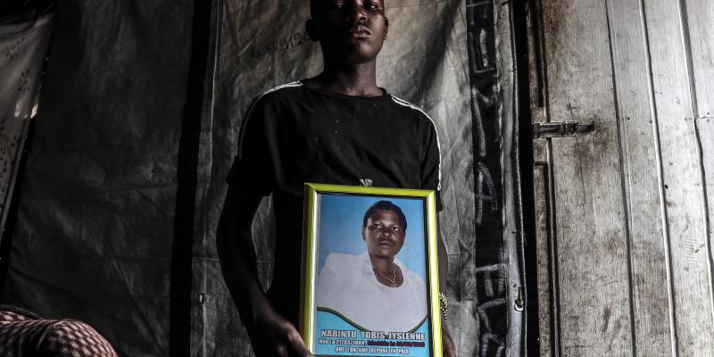 Un jeune adolescent, porte le portrait de sa mère, Nabintu Tobis, tuée devant une pharmacie