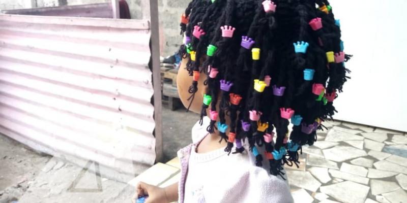 Petite fille portant une perruque confectionnée par Lucie Lusamba