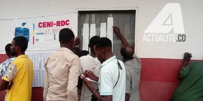 Les électeurs consultent les résultats devant un bureau de vote à Bandundu