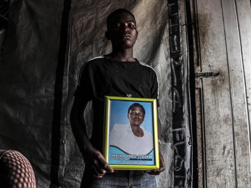 Un jeune adolescent, porte le portrait de sa mère, Nabintu Tobis, tuée devant une pharmacie