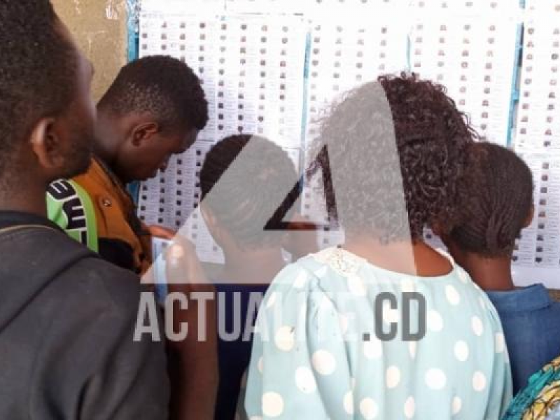 Les électeurs cherchent leurs noms sur les listes affichées au bureau de vote à Kolwezi.