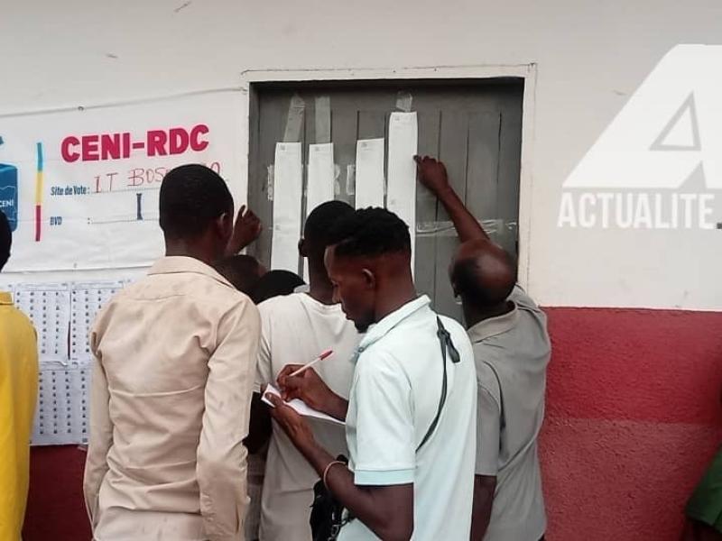Les électeurs consultent les résultats devant un bureau de vote à Bandundu