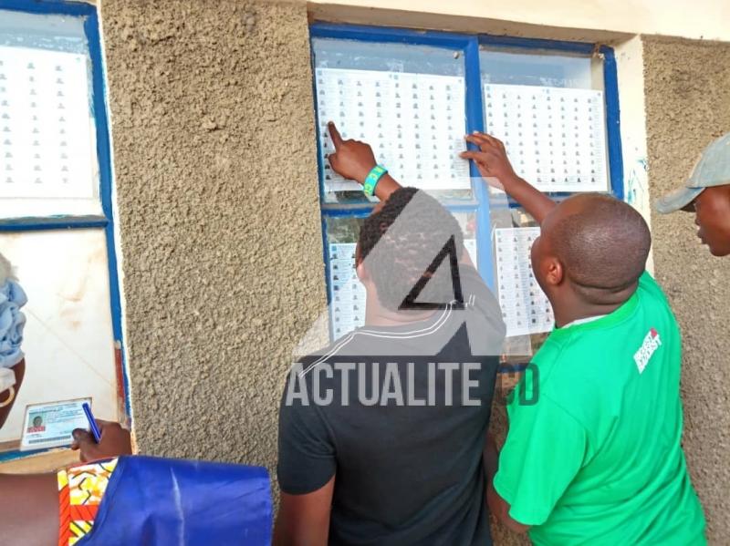 Les électeurs vérifient leurs noms sur les listes affichées devant le bureau de vote.
