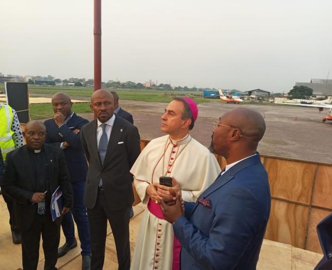 Patrick Muyaya et Mgr Ettore Balestrero (Nonce apostolique) à l’aéroport de Ndolo