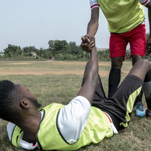 Un joueur de football aidant un coéquipier à se relever sur le terrain
